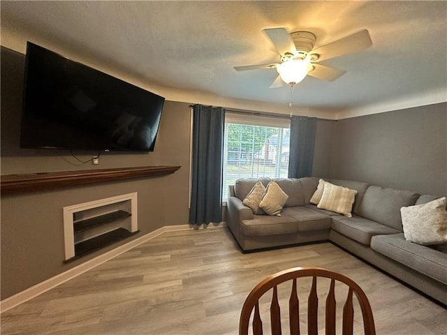 living room featuring ceiling fan, a textured ceiling, and light hardwood / wood-style flooring