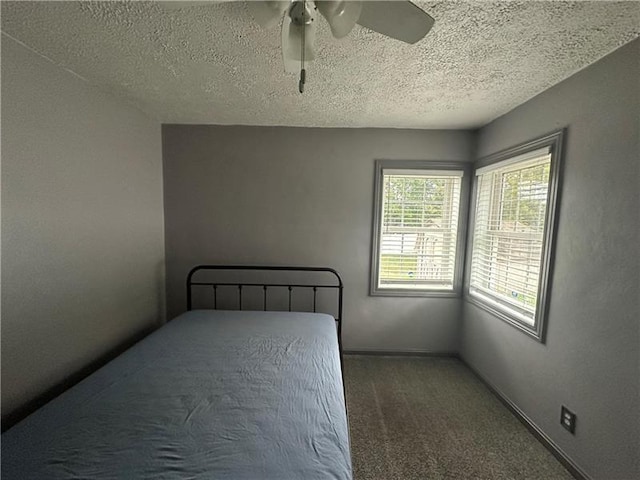 unfurnished bedroom with carpet flooring, ceiling fan, and a textured ceiling