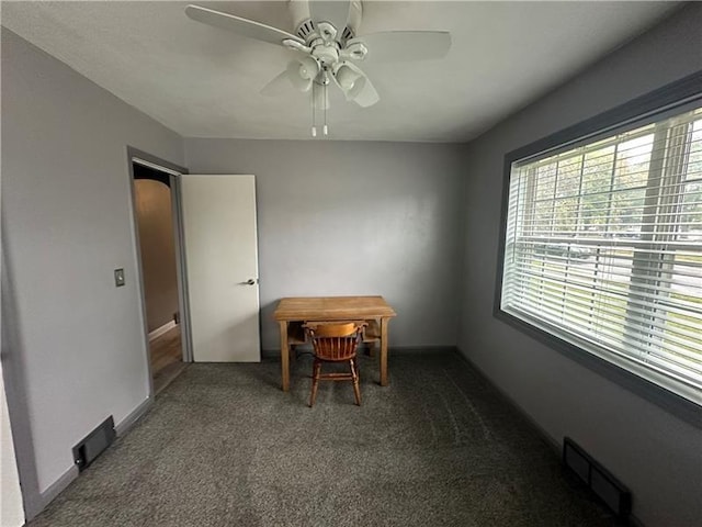 dining space featuring ceiling fan and dark colored carpet