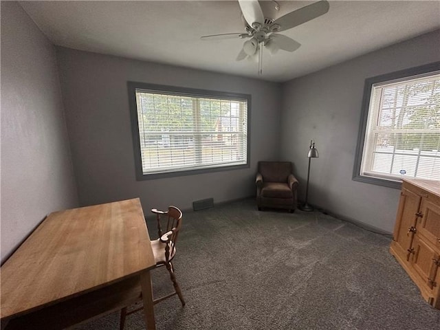 living area featuring dark colored carpet, plenty of natural light, and ceiling fan