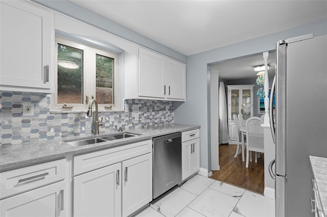 kitchen with white cabinets, decorative backsplash, stainless steel appliances, and sink