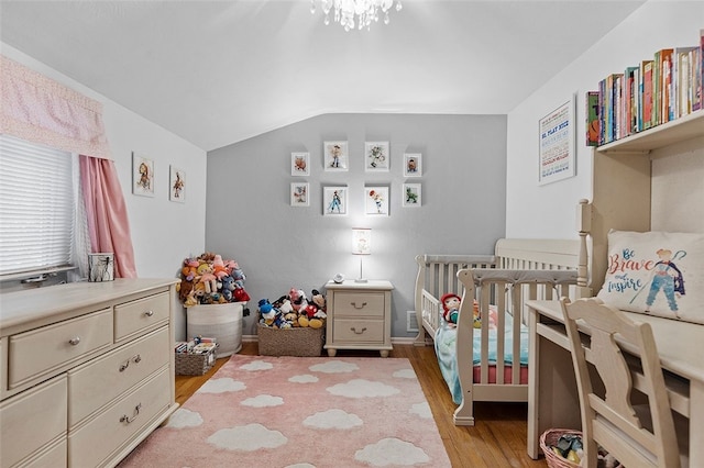 bedroom with vaulted ceiling, light hardwood / wood-style flooring, and a crib