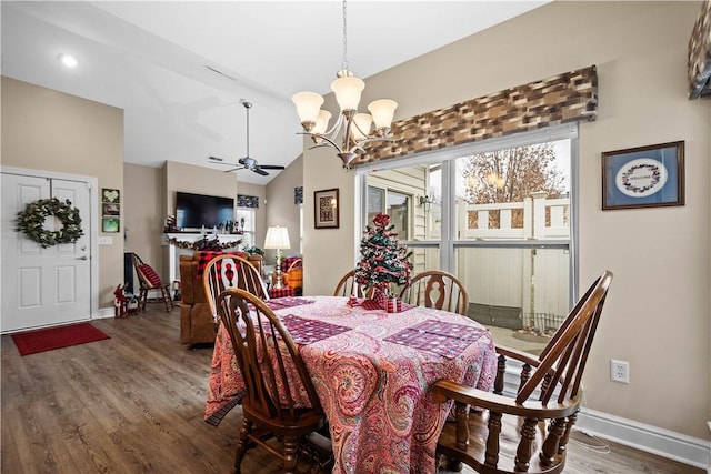 dining area featuring hardwood / wood-style floors, ceiling fan with notable chandelier, and vaulted ceiling