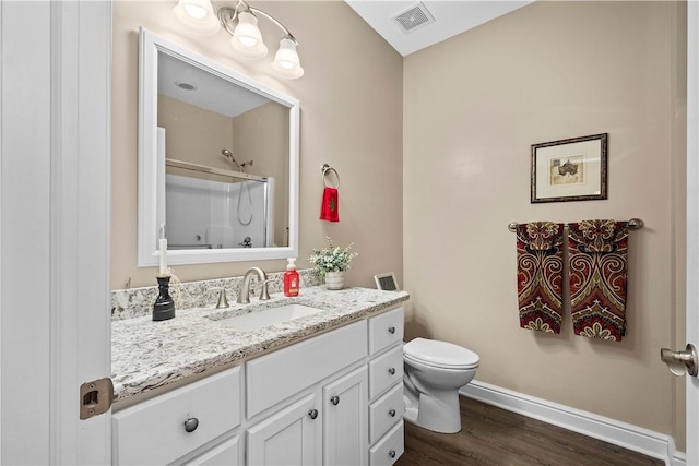 bathroom with hardwood / wood-style floors, vanity, toilet, and walk in shower