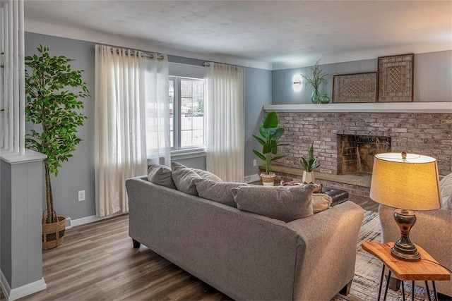 living room featuring wood-type flooring and a brick fireplace