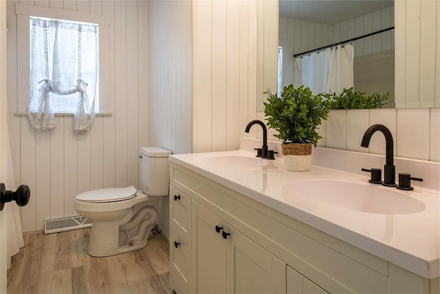 bathroom with wood walls, vanity, wood-type flooring, and toilet