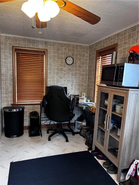 office space featuring ceiling fan, crown molding, and tile walls