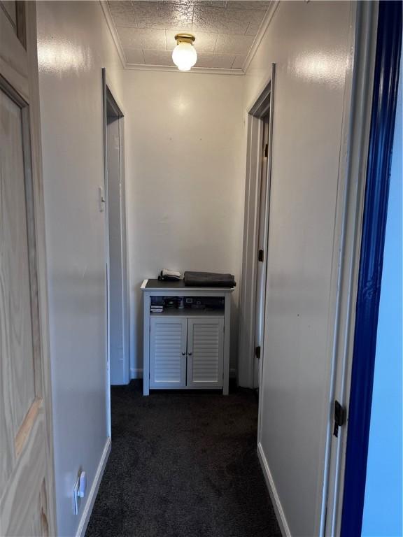 corridor with dark carpet and ornamental molding