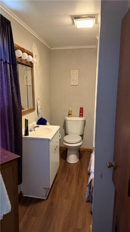 bathroom with crown molding, hardwood / wood-style floors, vanity, and toilet