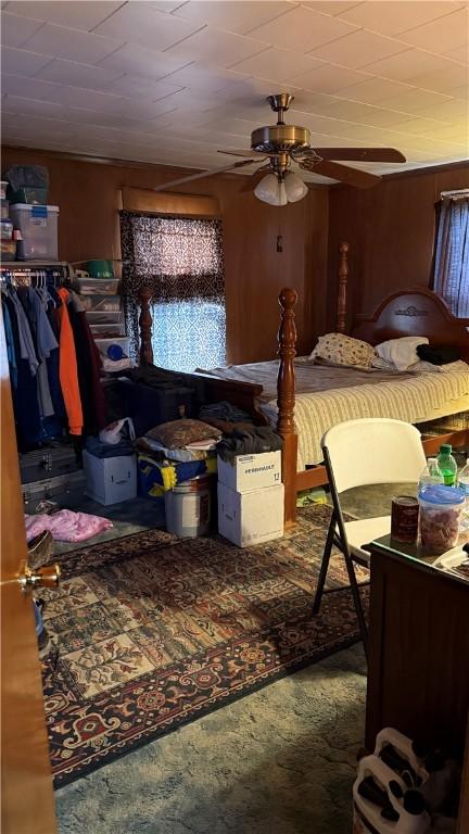 bedroom featuring carpet, ceiling fan, and wooden walls