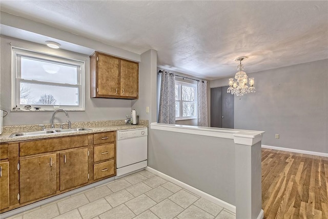 kitchen with dishwasher, sink, an inviting chandelier, light hardwood / wood-style floors, and pendant lighting