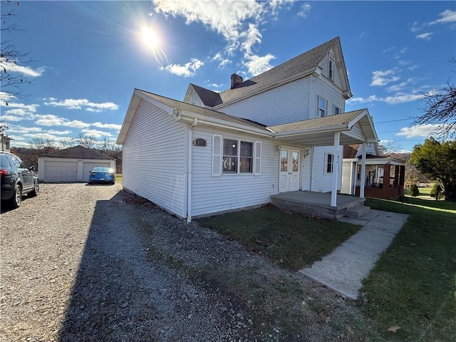 view of front facade featuring french doors, an outdoor structure, a front lawn, covered porch, and a garage