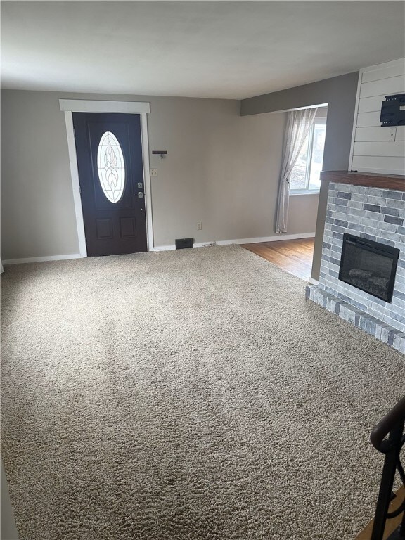 entryway featuring wood-type flooring and a brick fireplace