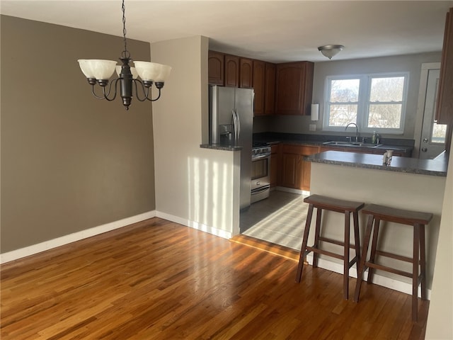 kitchen with sink, dark wood-type flooring, a breakfast bar area, appliances with stainless steel finishes, and hanging light fixtures