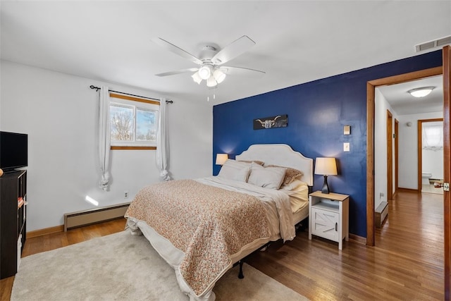 bedroom with wood-type flooring, ceiling fan, and a baseboard heating unit