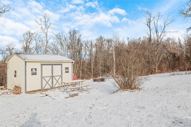 snow covered structure with an outdoor fire pit