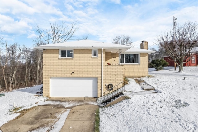 snow covered rear of property with a garage