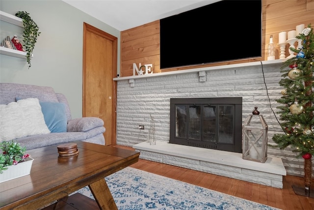 living room featuring wooden walls, a fireplace, and hardwood / wood-style floors