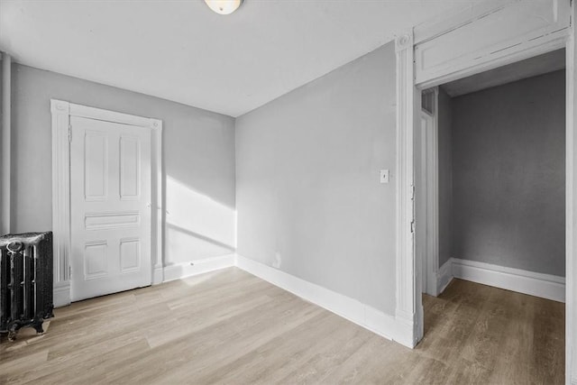 empty room featuring radiator heating unit and light wood-type flooring