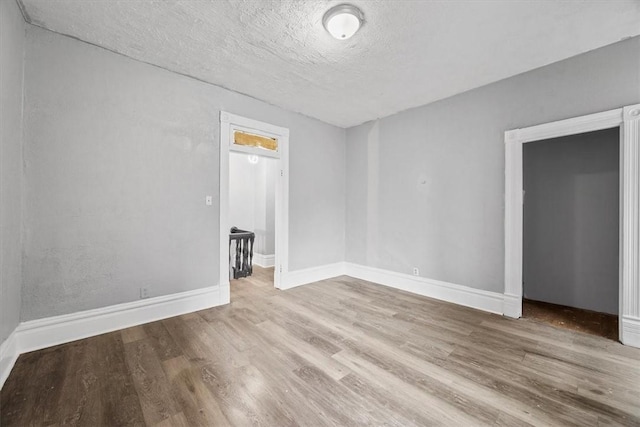 unfurnished room with a textured ceiling and light hardwood / wood-style floors