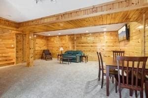 dining room featuring carpet flooring and wooden walls