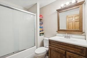 full bathroom featuring vanity, combined bath / shower with glass door, and toilet