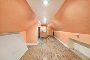 additional living space with lofted ceiling and light hardwood / wood-style flooring