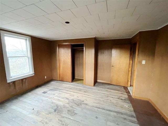 unfurnished bedroom with light wood-type flooring and wood walls