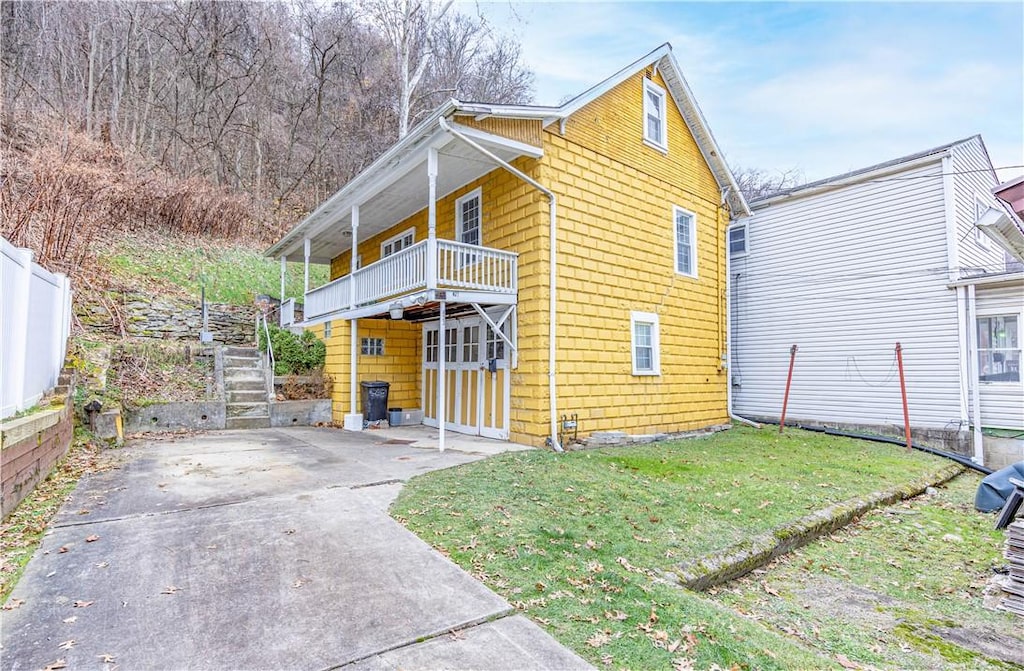 view of side of property with a yard and a balcony