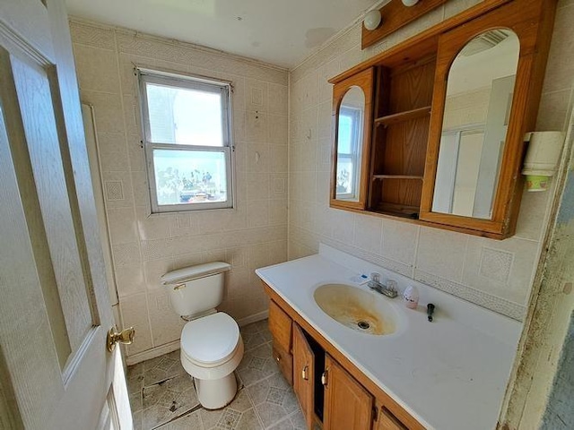 bathroom featuring vanity, toilet, and tile walls