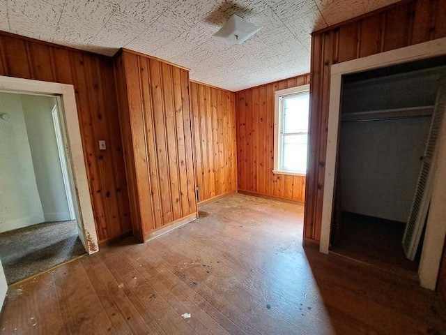 unfurnished bedroom with a closet, hardwood / wood-style floors, and wood walls