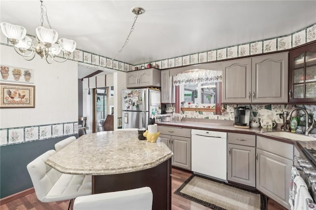 kitchen with sink, stainless steel appliances, an inviting chandelier, dark hardwood / wood-style floors, and a kitchen island