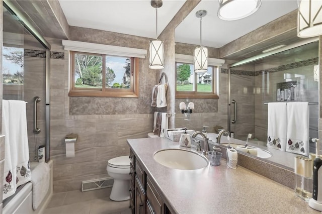 full bathroom with shower / bath combination with glass door, vanity, toilet, and tile walls