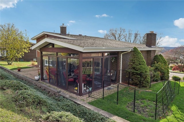 rear view of property with a lawn and a sunroom