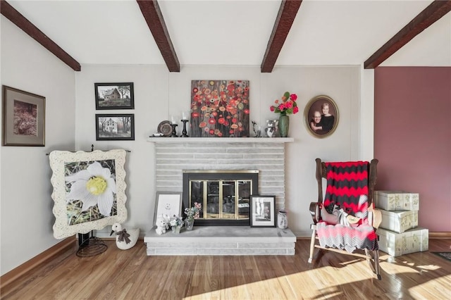 living area with hardwood / wood-style flooring, a fireplace, and beamed ceiling