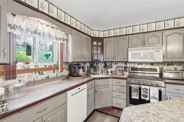 kitchen with backsplash, sink, hardwood / wood-style floors, and white appliances