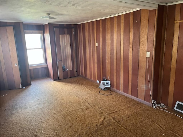 carpeted spare room featuring a wall unit AC, a textured ceiling, and wood walls