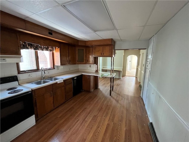 kitchen with arched walkways, electric range, under cabinet range hood, a sink, and a paneled ceiling