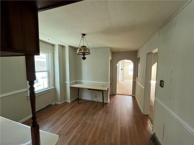 unfurnished dining area with arched walkways, visible vents, wood finished floors, and baseboards