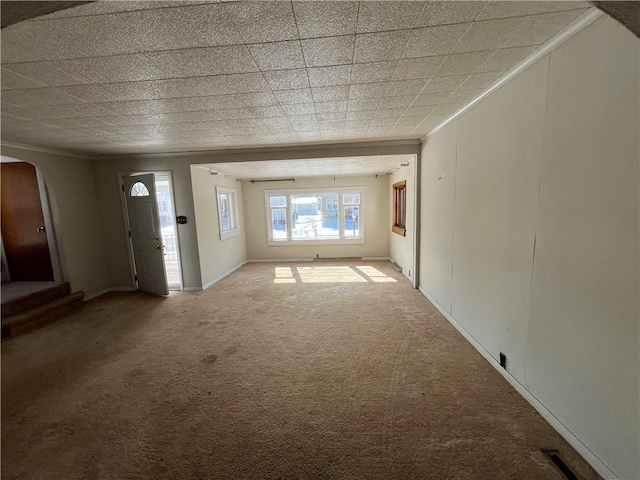 unfurnished living room featuring visible vents, arched walkways, carpet floors, and crown molding