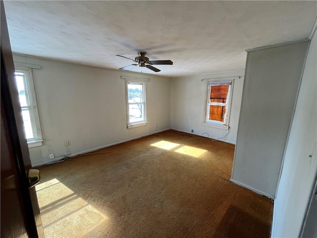 carpeted empty room with ceiling fan and baseboards