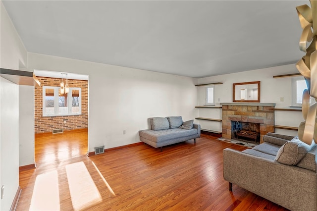 living room featuring a fireplace, wood-type flooring, and brick wall