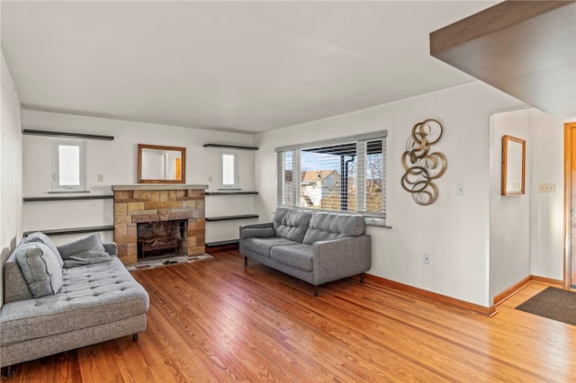 living room with light hardwood / wood-style flooring and a stone fireplace