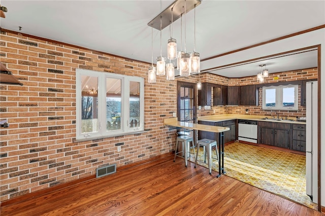 kitchen with dark brown cabinets, brick wall, white appliances, and light wood-type flooring