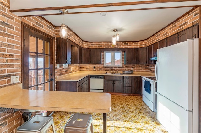 kitchen with sink, brick wall, kitchen peninsula, decorative light fixtures, and white appliances