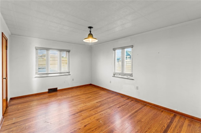 empty room featuring crown molding, plenty of natural light, and hardwood / wood-style flooring