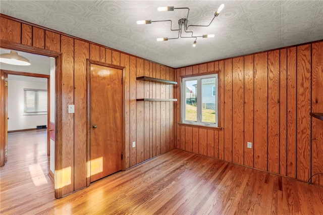 interior space with wooden walls, light hardwood / wood-style flooring, and a notable chandelier