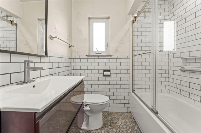 full bathroom with toilet, tile patterned flooring, tile walls, and combined bath / shower with glass door