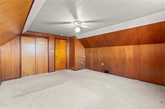 bonus room featuring ceiling fan, light carpet, wooden walls, and vaulted ceiling