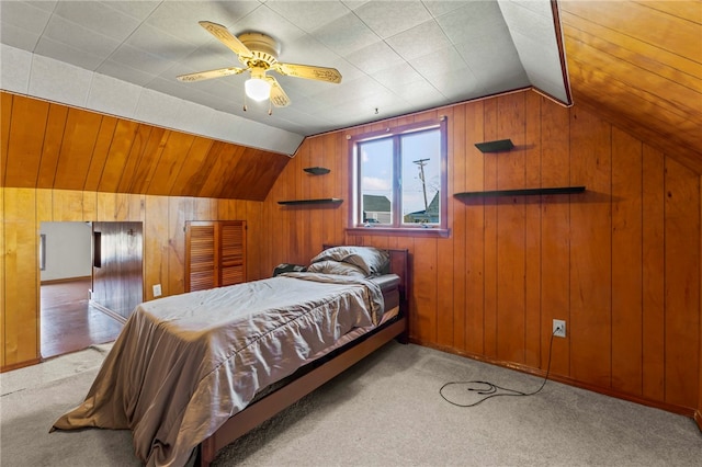 bedroom featuring wood walls, ceiling fan, light carpet, and vaulted ceiling